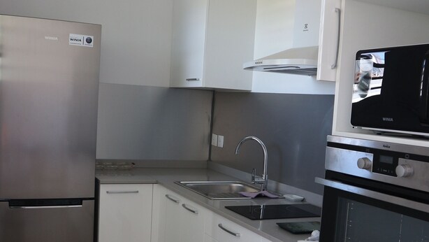 A modern kitchen with white cabinets, stainless steel appliances, and a tiled floor.