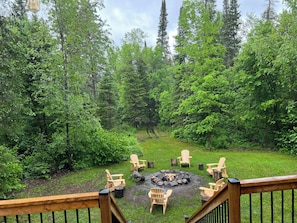 Relax by the fire pit surrounded by Adirondack chairs on a serene outdoor deck.