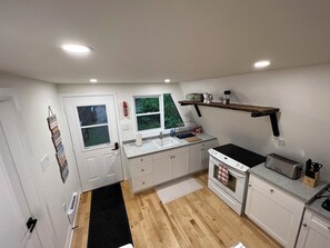 Compact kitchen with oven, toaster, and sink, featuring a window above for natural light.
