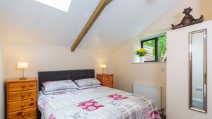 A bedroom with a bed, dresser, window, and a mirror. - Stables Cottage - deep in the Devon countryside (Holsworthy)