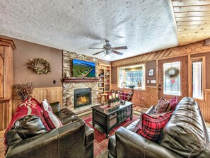 Ein gemütliches Wohnzimmer mit Kamin, Ledersofas und einem darüber montierten Fernseher.