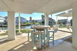 Un'area esterna coperta con tavolo e sedie, affacciata su uno specchio d'acqua e palazzi residenziali.