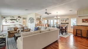 A spacious living room with a large sofa, two armchairs, and a dining area with a wooden table and chairs.