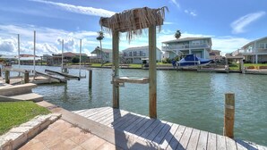 A waterfront property with a wooden dock, a thatched structure, and a blue boat.