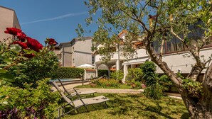 Un patio con piscina, sillas de descanso y un jardín con diversas plantas y flores.