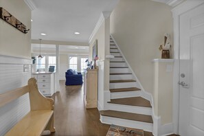 Eine Treppe mit Holzboden und weißen Wänden, die zu einer Tür mit einer Dekoration darüber führt.