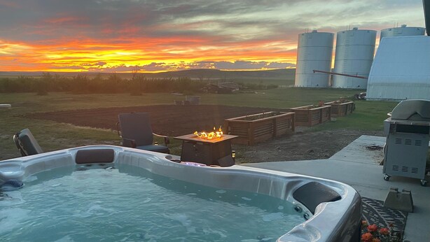 Jacuzzi amb un foc central, envoltat d'una zona verda i vistes al capvespre.