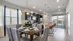 Una cocina moderna con armarios oscuros, una isla central e iluminación colgante.