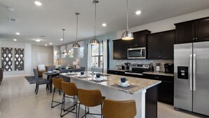 Una cocina moderna con electrodomésticos de acero inoxidable, una isla de granito e iluminación colgante.