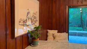 A wooden interior with a framed artwork, a potted plant, and a bed with pillows. - Mid-Century Gem • Creekside • King Beds • Near UNC (Chapel Hill)