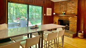 A modern kitchen with a large island, wooden walls, and a brick fireplace. - Mid-Century Gem • Creekside • King Beds • Near UNC (Chapel Hill)