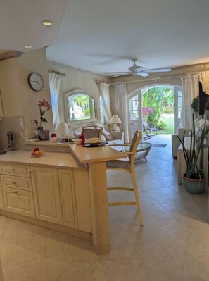 A spacious kitchen with a large island, wooden cabinets, and a dining area with a chair. - Sugar Hill Resort, St.James (Mount Standfast)