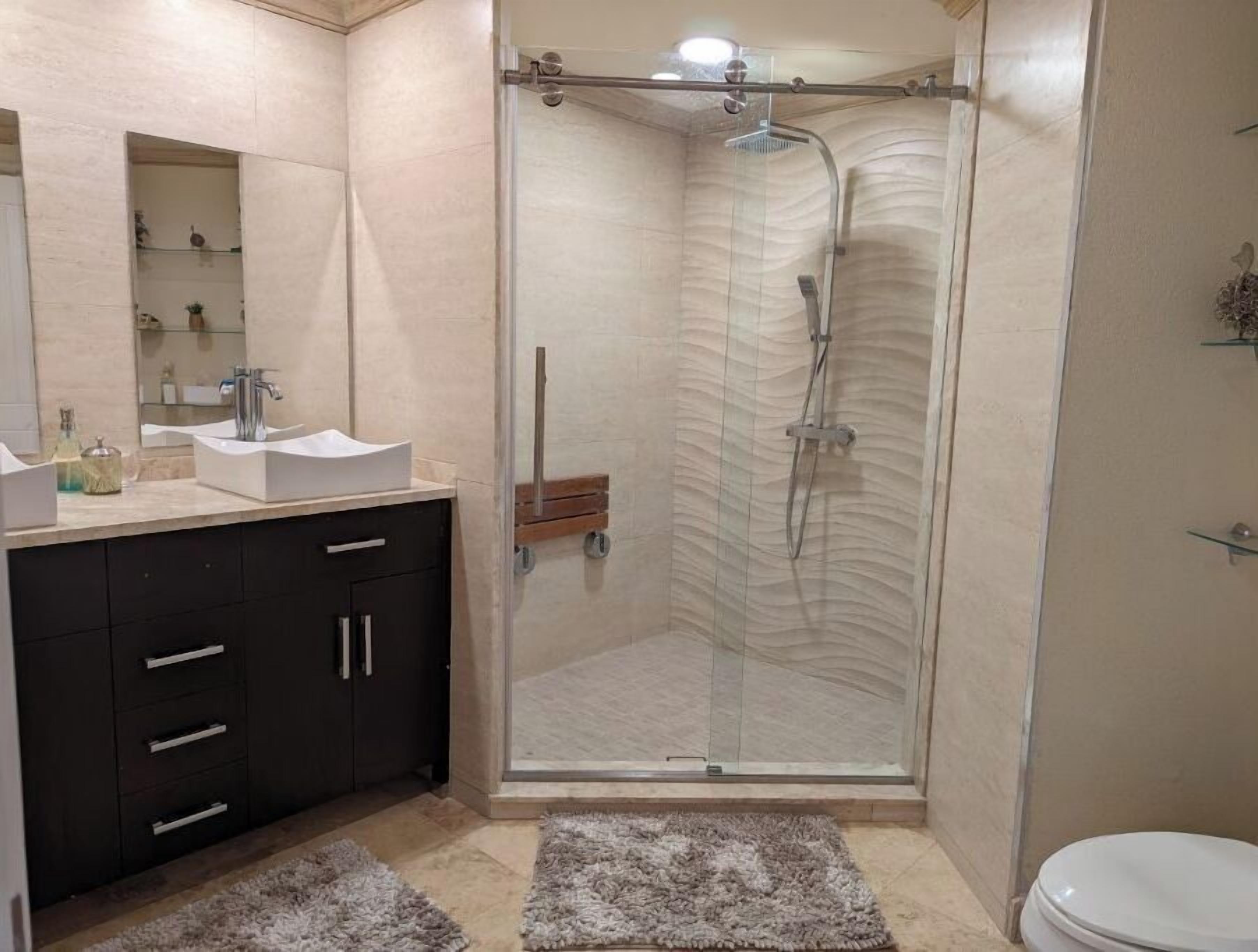 Ein modernes Badezimmer mit einer Duschkabine, einem Waschtisch inklusive Spiegel und einer Toilette.