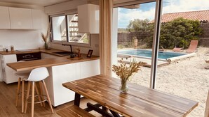 A modern kitchen with a large island, bar stools, and a view of a backyard with a pool. - "La Villa Tchanquée " Dominant view of the Ocean & Pines (Soorts-Hossegor)