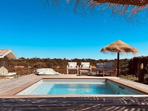 A swimming pool with a wooden deck, lounge chairs, and a thatched umbrella. - "La Villa Tchanquée " Dominant view of the Ocean & Pines (Soorts-Hossegor)