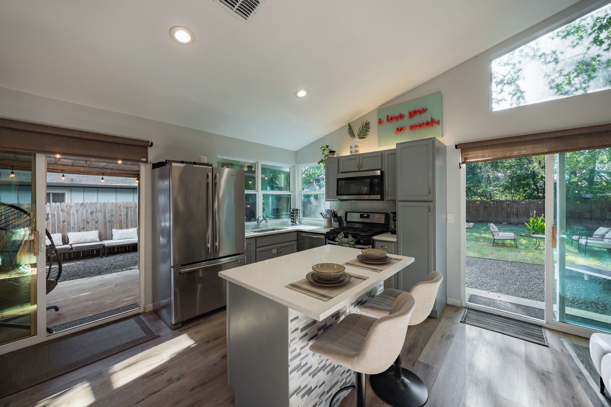 Una cocina moderna con una isla central, electrodomésticos de acero inoxidable y ventanas amplias.