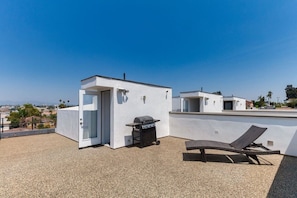 Une terrasse sur le toit équipée d’un barbecue, d’une porte et d’un fauteuil de relaxation.