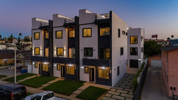 A modern multi-story residential building with balconies, large windows, and a well-maintained lawn. - Modern 4 Bedroom Charmer w/ Rooftop Deck House #2  (Los Angeles)