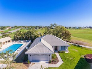 A residential property with a swimming pool, a garage, and a view of a golf course. - Family friendly (Naples)