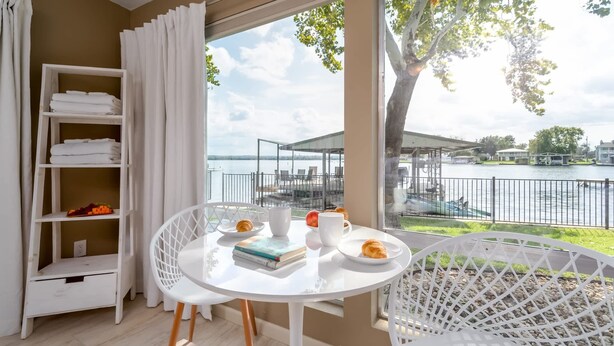 Ein Balkon mit einem Frühstückstisch, einem weißen Stuhl und einem Regal mit gefalteten Handtüchern.