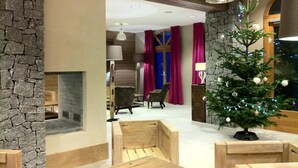 A modern interior with a stone accent wall, a fireplace, wooden seating, and a decorated Christmas tree.