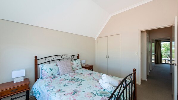 A bedroom with a bed, nightstands, a wardrobe, and a view of the outdoors.