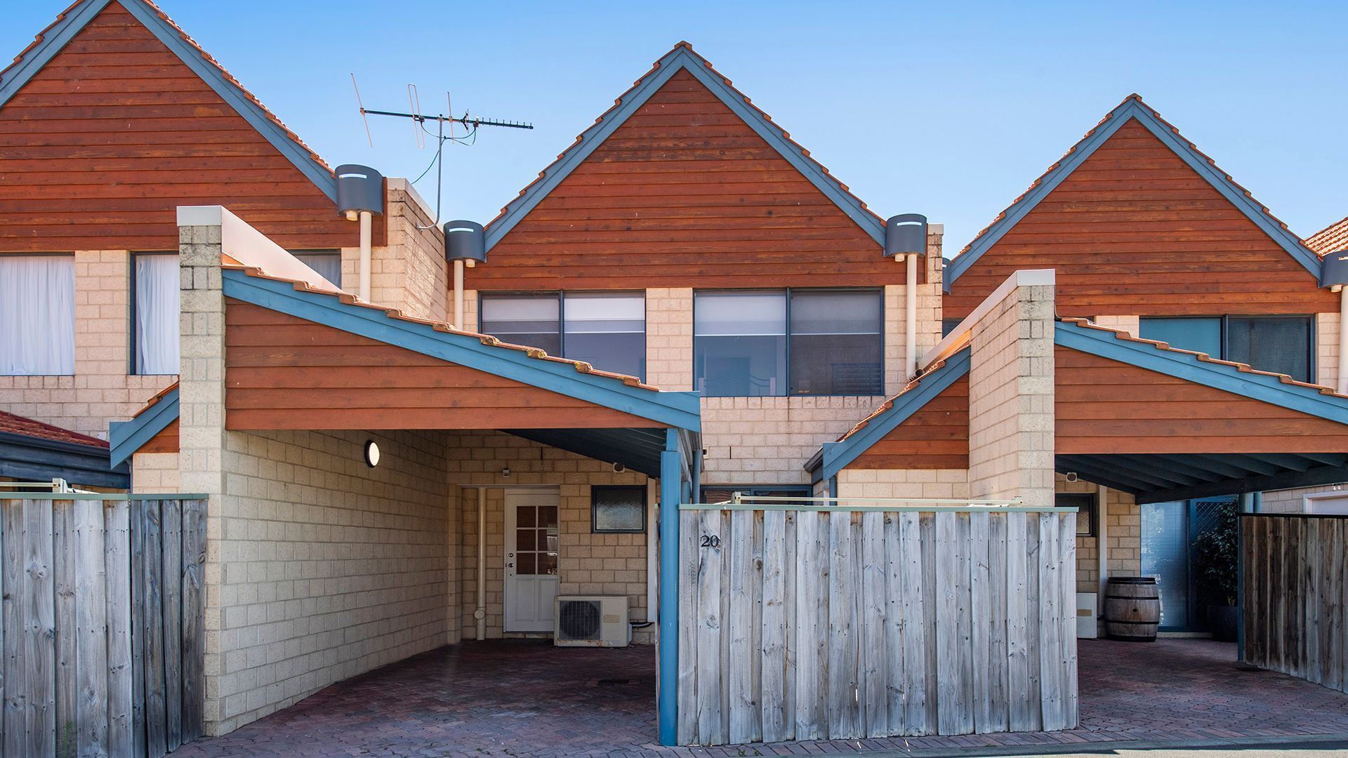 A row of wooden houses with pitched roofs and a central entrance.