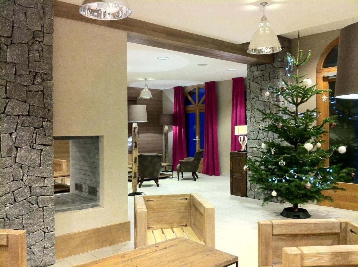 Un intérieur moderne avec un mur d’accent en pierre, une cheminée, des sièges en bois et un sapin de Noël décoré.