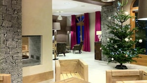 A modern interior with a stone accent wall, a fireplace, wooden seating, and a decorated Christmas tree.