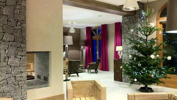 Un intérieur moderne avec un mur d’accent en pierre, une cheminée, des sièges en bois et un sapin de Noël décoré.