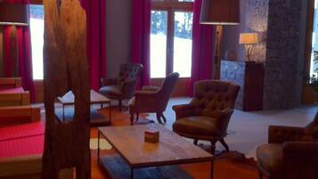 Un vaste salon doté d’un mur en pierre, de fauteuils en cuir, d’une table basse en bois et d’une grande fenêtre agrémentée de rideaux.