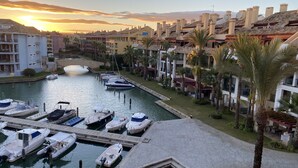 A marina with boats docked, a bridge, and buildings with balconies and palm trees. - Luxury apartment with lovely views over Marina (Marina de Sotogrande, San Roque)