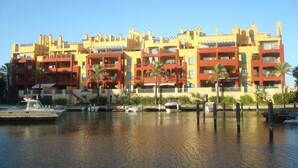 A multi-story hotel with balconies, located near a body of water with boats docked. - Luxury apartment with lovely views over Marina (Marina de Sotogrande, San Roque)