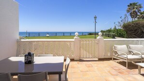 Un patio con tavolo e sedie, vista sul mare e un lampione.