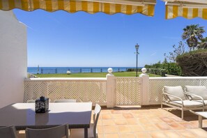 A patio with a table and chairs, a view of the sea, and a lamp post.