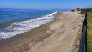 Una spiaggia con cielo sereno, mare calmo e alcune persone.