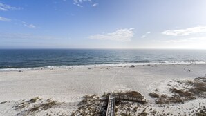 A beach with a wooden boardwalk leading to the water, sandy beach, and ocean view. - Pelican Pointe 702 by Liquid Life (Orange Beach)