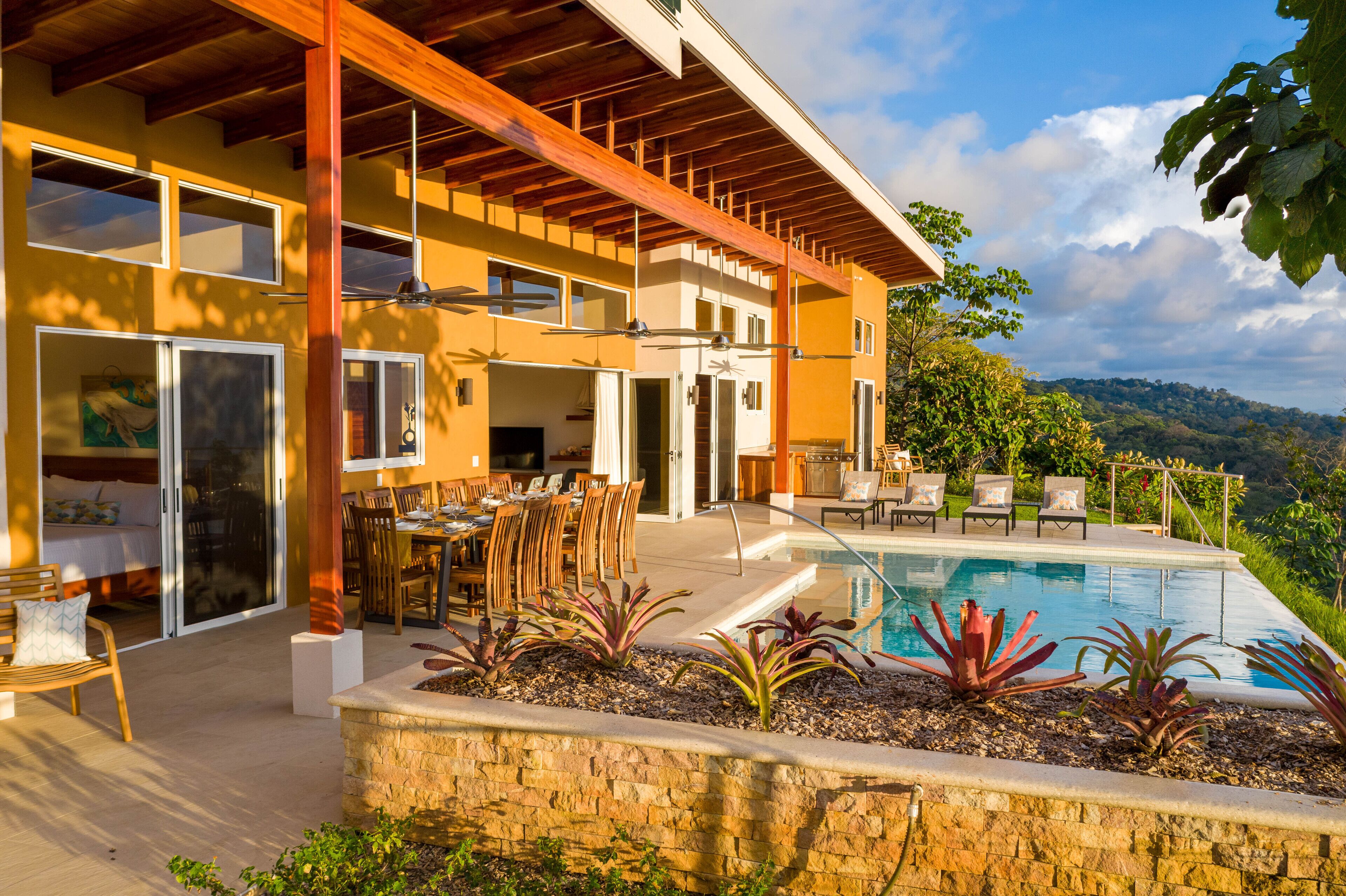 A modern house with a pool, patio furniture, and a view of the hills.