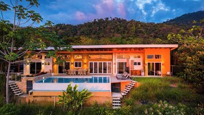 A modern house with a swimming pool, a staircase leading to the entrance, and a lush garden. - Luxury retreat with panoramic ocean view, private infinity pool, concierge (Uvita)