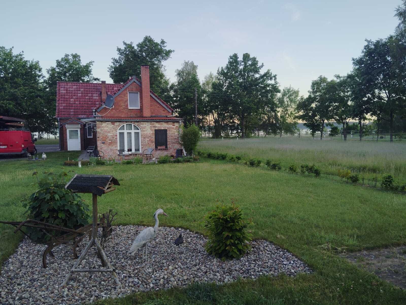 Una casa con tejado rojo, fachada de piedra y un área de grava con un comedero para pájaros.