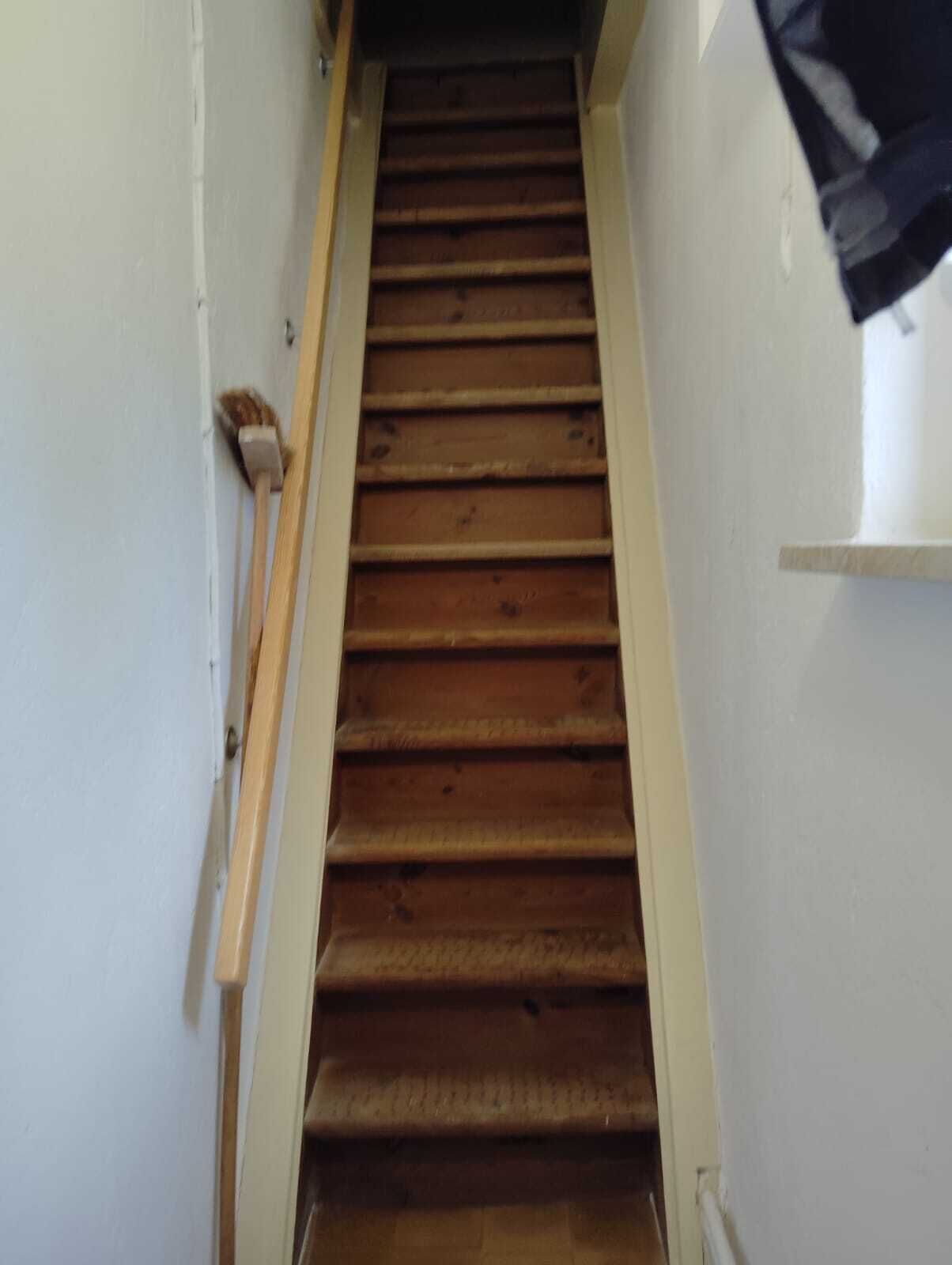 Eine Holztreppe mit Handlauf, die zu einer Zwischenebene führt.