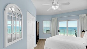 Una camera da letto con un letto grande, un ventilatore a soffitto e vista sulla spiaggia.
