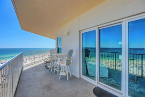 Relax on the balcony with a clear view of the beach, featuring a set of chairs and a table.