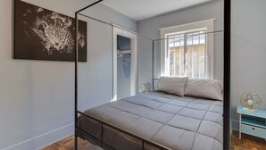 Een slaapkamer met een bed, een raam en een spiegel.