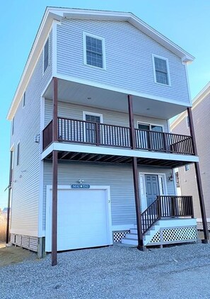 A two-story building with a garage door labeled "MAI TAI" and a balcony with a wooden railing. - 3-bd/3-bth, short walk to Salisbury beach and center - Winter Rentals Available (Salisbury)