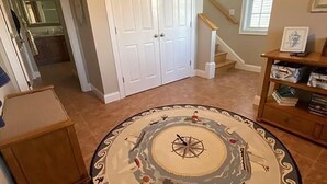 A hallway with a round rug featuring a compass design, a closed door, a staircase, and a window. - 3-bd/3-bth, short walk to Salisbury beach and center - Winter Rentals Available (Salisbury)