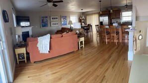 A spacious living area with a wooden floor, a sofa, a fireplace, and a dining area with chairs and a table. - 3-bd/3-bth, short walk to Salisbury beach and center - Winter Rentals Available (Salisbury)