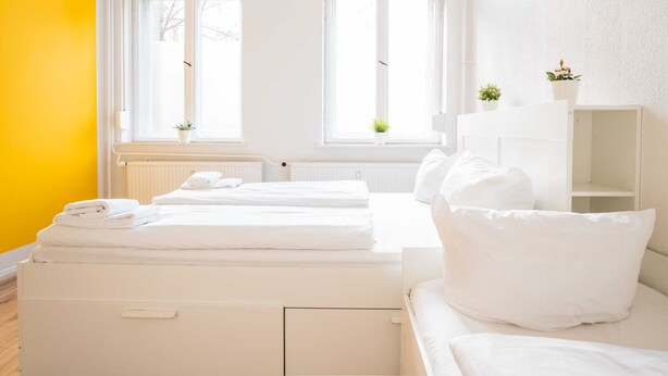 A bright room with a bed, a white wardrobe, and a window with a view of trees.