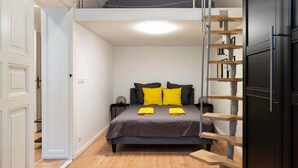Een compacte slaapkamer met een stapelbed, een nachtkastje en een ingebouwde plank.