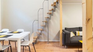 Een modern interieur met een trap, een eethoek en een bank.